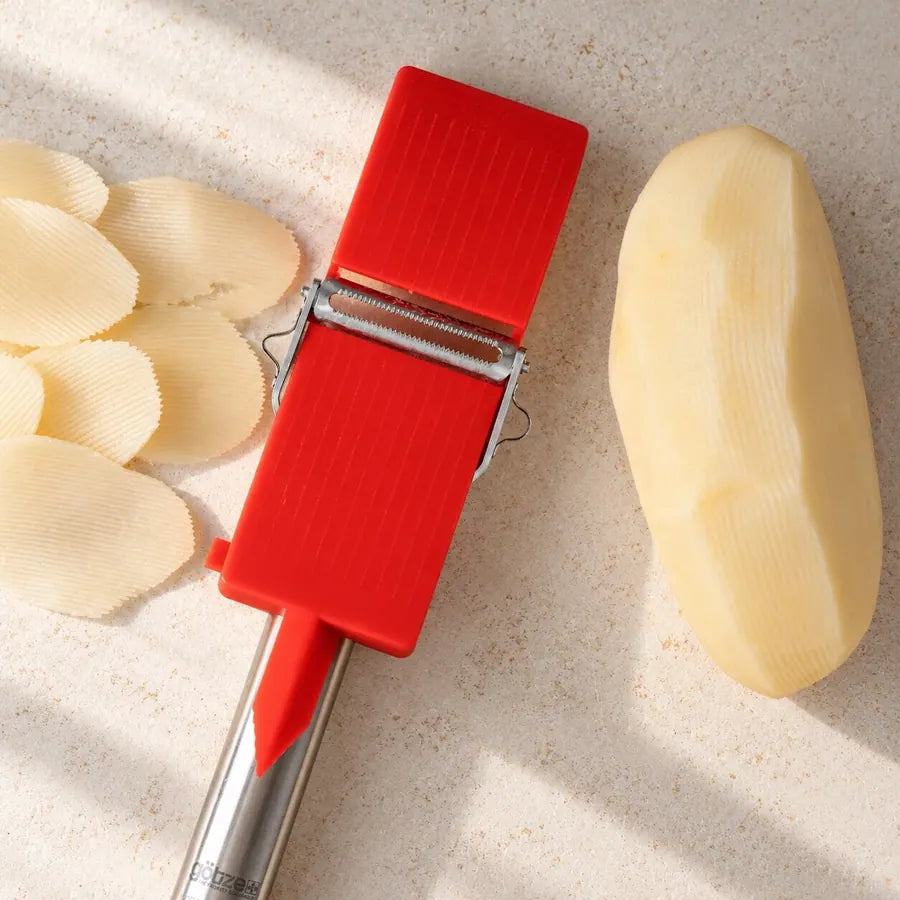 Götze red mini slicer beside thin potato slices and a peeled potato