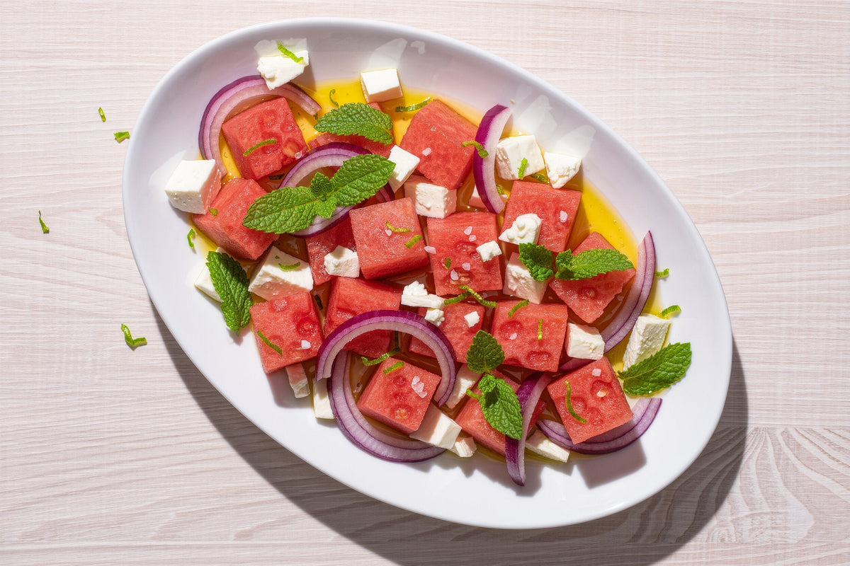 Watermelon cubes with crumbled feta, red onion and fresh mint on a platter
