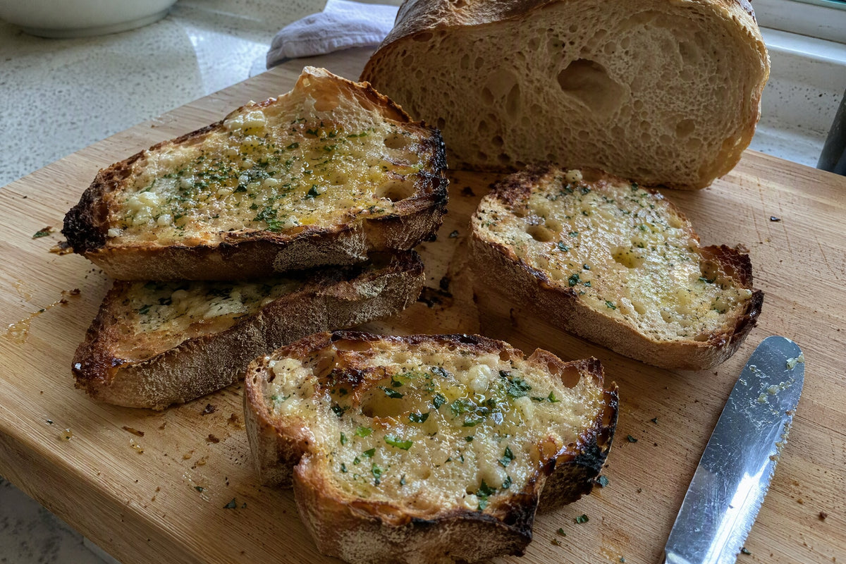 Slices of golden garlic butter sourdough toast with parsley on a wooden board