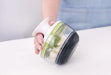 Götze Mavo manual food chopper held in hand with garlic cloves inside the clear container, featuring green blades and a black non-slip base.