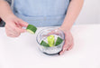 Götze Mavo manual food chopper with stainless steel blades and fresh cucumber pieces placed inside the clear chopping container.