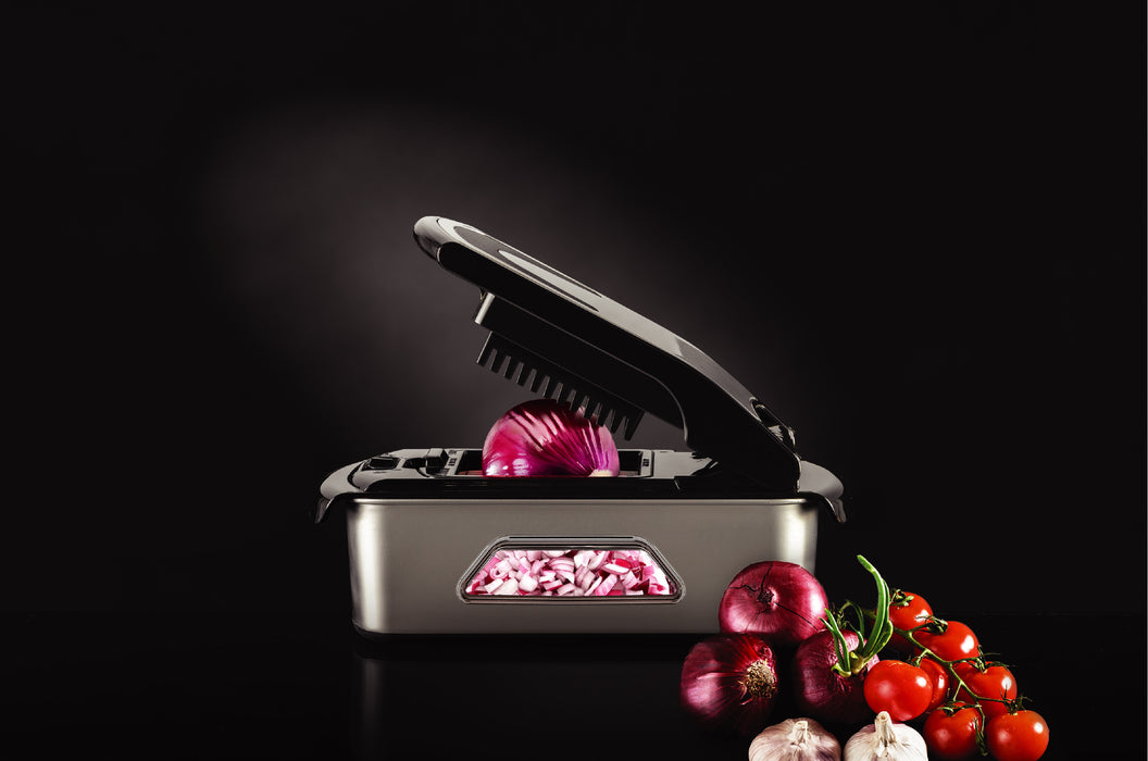 Götze Premium Stainless Steel Food Chopper dicing red onion into even pieces, displayed with fresh onions, tomatoes, and garlic on a dark background.