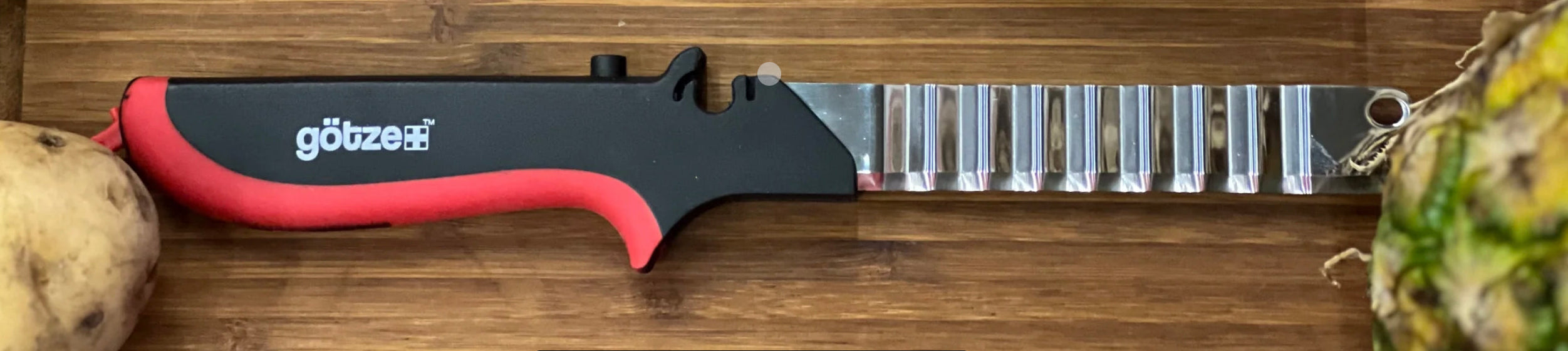 Götze Replacement Wavy Blade for Kitchen Shears with a black and red ergonomic handle displayed on a wooden cutting board.