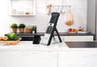 Götze SafeSlice Pro mandoline slicer with adjustable stand and clear collection container displayed on a modern kitchen countertop.