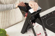 Götze SafeSlice Pro mandoline slicer being used to slice fresh radishes safely into a clear collection container.