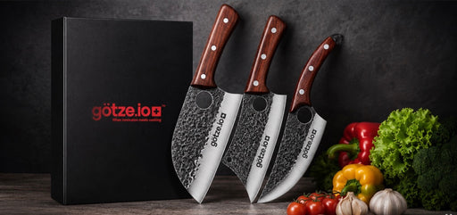 Götze 3-piece hammered stainless steel kitchen knife set with wooden handles, black gift box, and fresh vegetables displayed on a dark kitchen background.