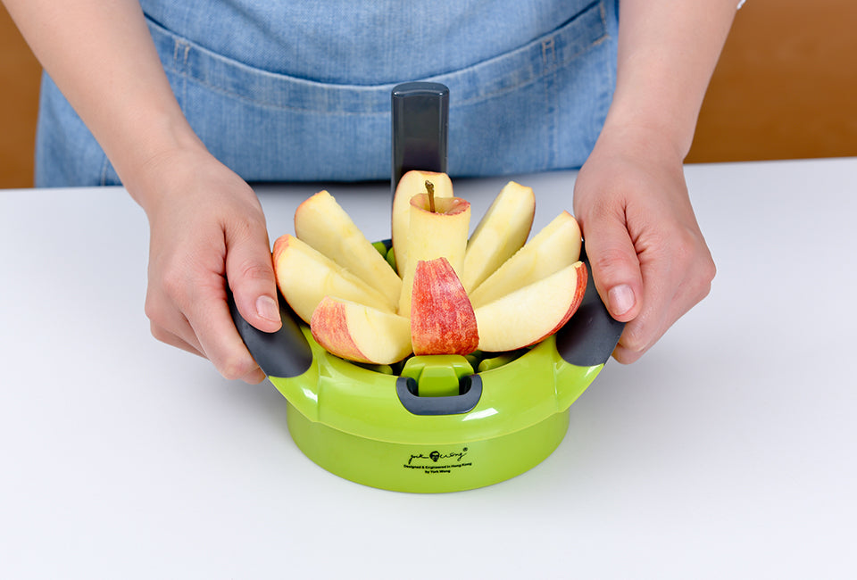 Götze 2-in-1 food divider slicing a fresh apple into even wedges while separating the core with its green and black cutting base.