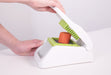 Götze FreshCut Food Dicer being used to press a carrot through the green stainless steel cutting grid for quick, even dicing.