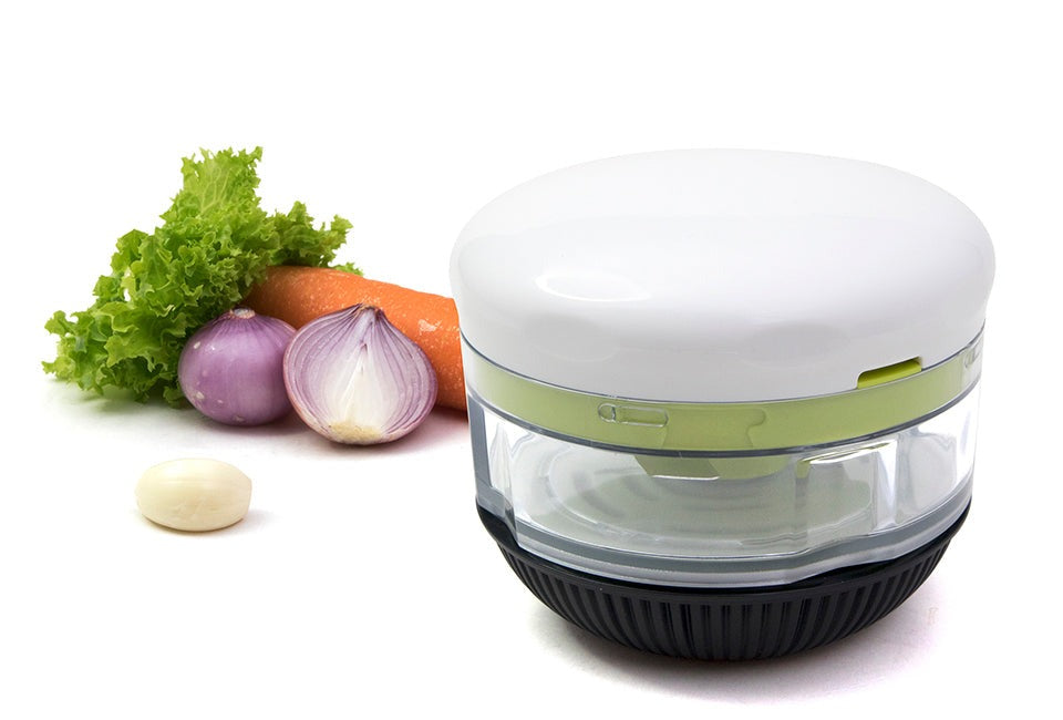 Götze Fresh Mavo manual food chopper with clear container, white lid, green blade system, and black non-slip base displayed with lettuce, carrot, red onion, and garlic.