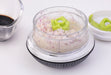 Götze Mini Mavo manual food chopper filled with finely chopped red onion, featuring a clear container, green blade system, and black non-slip base.