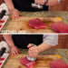 Götze Reversible Dual-Sided Meat Tenderizer & Pounder using the toothed side to pound and soften raw meat on a wooden cutting board.