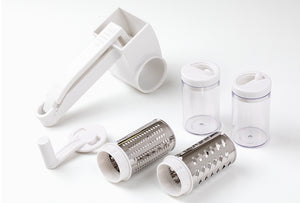Götze rotary grater set with hand crank, two interchangeable stainless steel grating drums, and two clear storage containers on a white background.