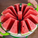 Götze watermelon slicer cutting a whole watermelon into 12 even wedges with a centered core and green ergonomic handles.