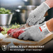 Premium Cut Resistant Glove worn while slicing raw meat with a chef knife, providing hand protection during food preparation.