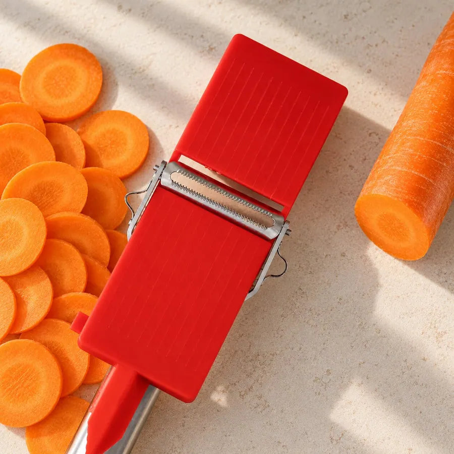 Götze red mini slicer with round carrot slices and a whole carrot on a stone countertop