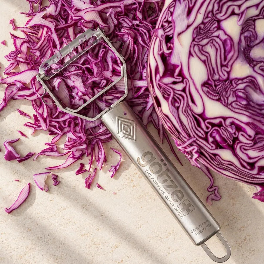 Götze julienne peeler beside shredded red cabbage and a halved cabbage