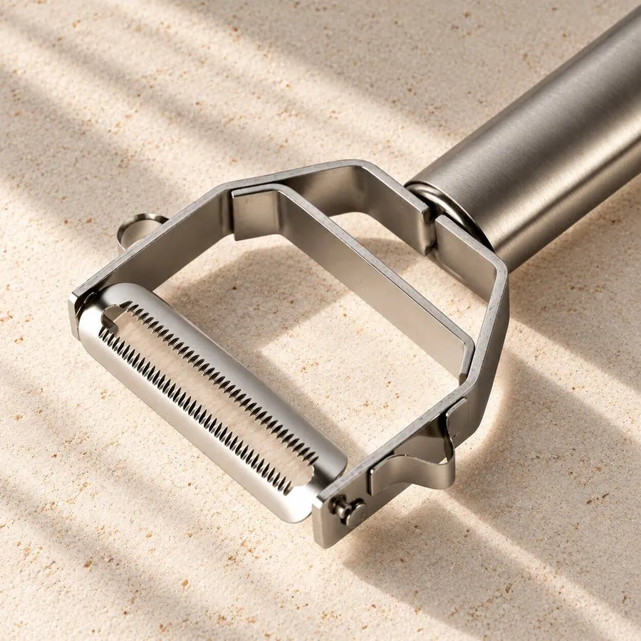 Close-up of the Götze julienne peeler blade in warm light on a stone surface